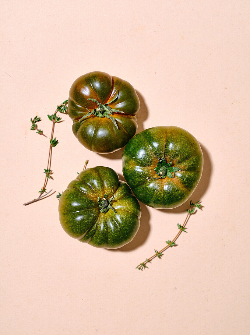 Green tomatoes in bright sunlight flat lay with copy space on beige background