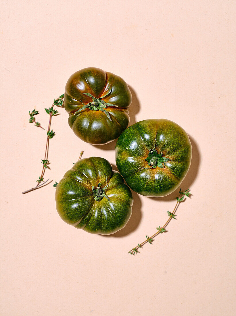 Grüne Tomaten in hellem Sonnenlicht, flach gelegt mit Kopierraum auf beigem Hintergrund