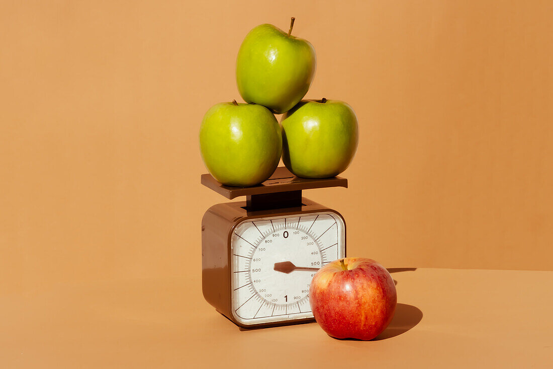 Fresh and juicy red and green apples on weighing scale as part of healthy calorie controlled diet on colored background