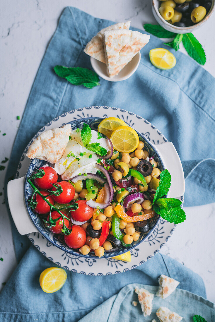 From above of delicious healthy salad with vegetables and herbs on plate over blur background