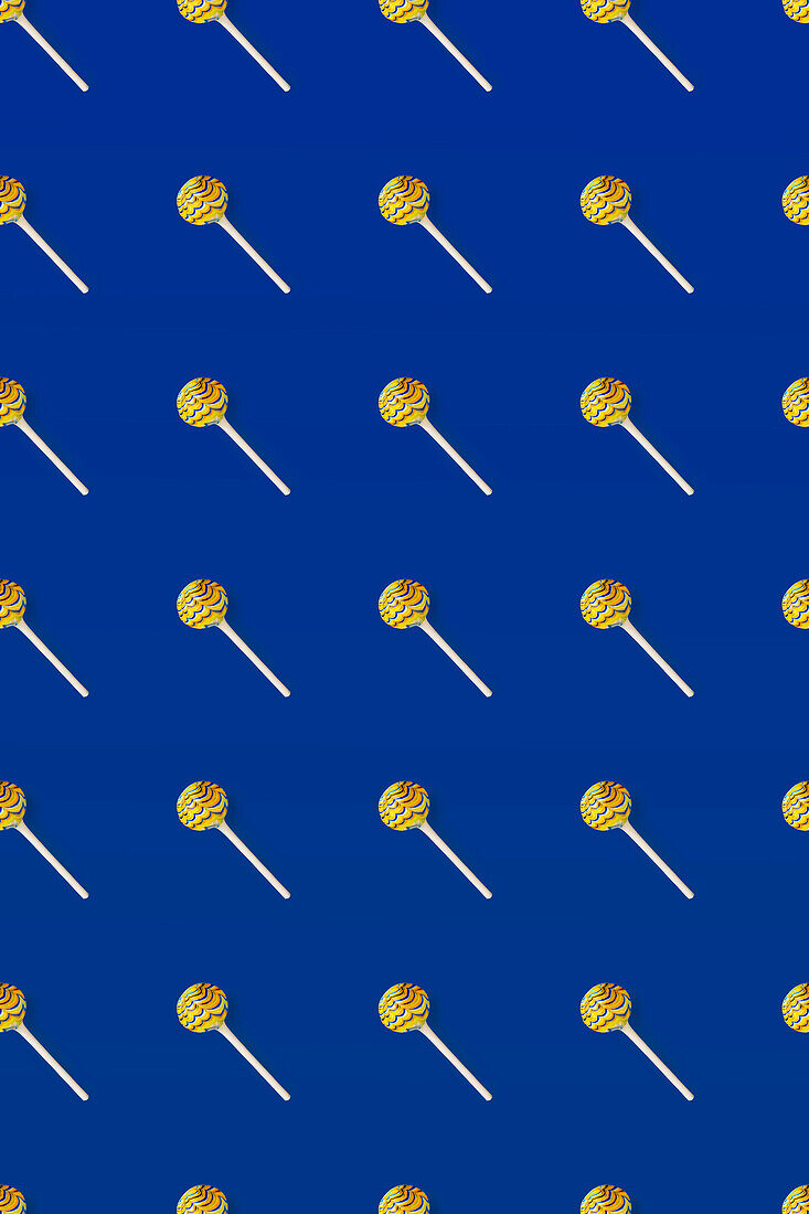 Top view of pattern of whole sweet crystal lollipops arranged on blue background