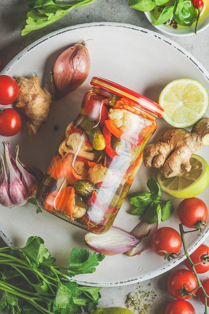 Top view of Close up of preserve jar with various pickled vegetables on plate with ingredients