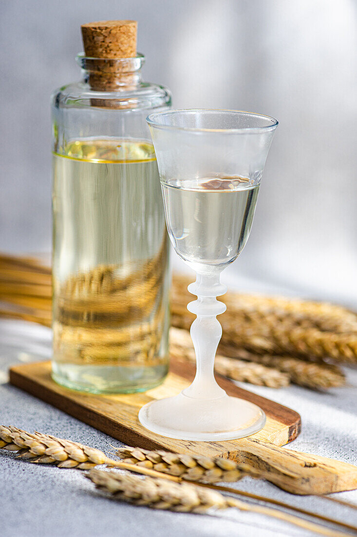 Traditional Ukrainian alcoholic drink made from wheat and known as Gorilka served in transparent glass near bottle placed on cutting board against blurred background