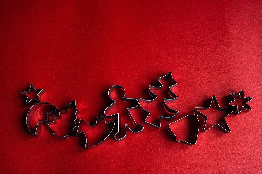 Top view of set of various cookie cutters located on red surface as symbol for Christmas holiday
