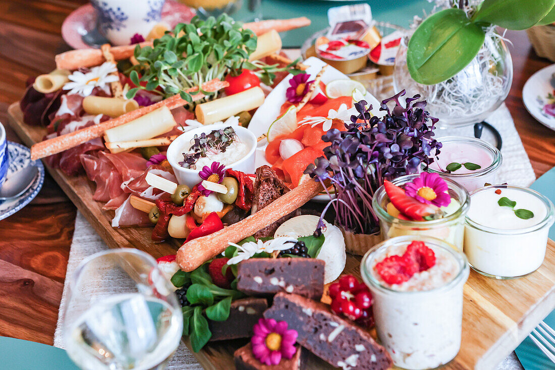 A vibrant gourmet charcuterie board filled with an assortment of cheeses, meats, and edible flowers.