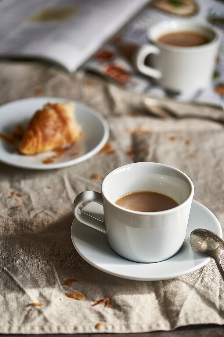Cozy coffee break with a fresh croissant on a rustic table.