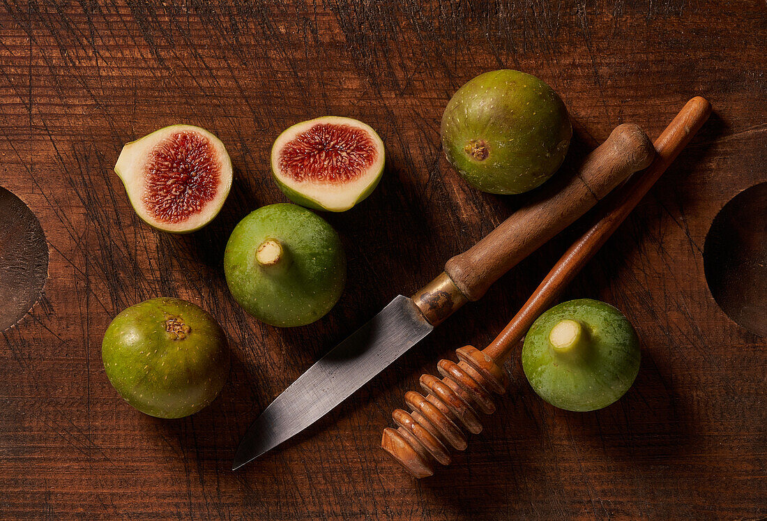 Frische Feigen mit einem Messer und Honiglöffel auf einem rustikalen Holztisch