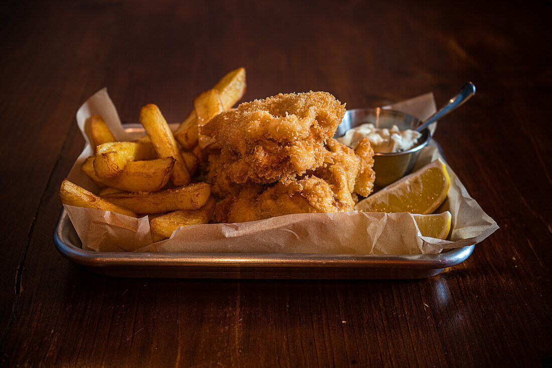 Traditional English dish Fish and chips served with french fries on wooden table