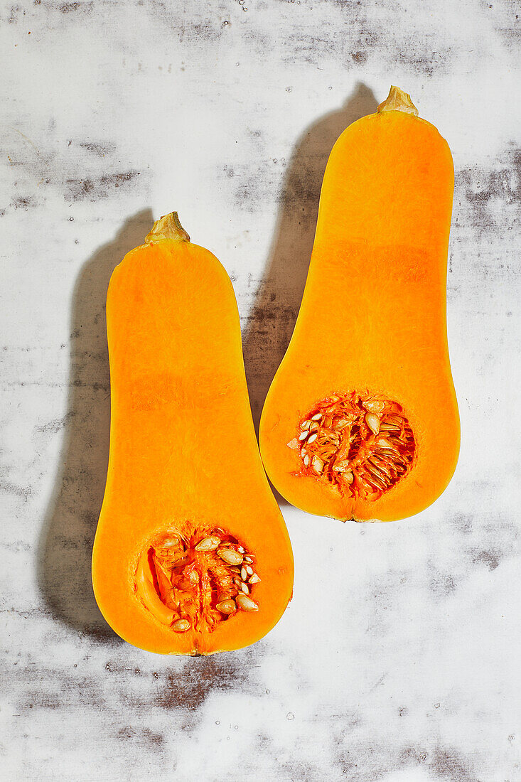 From above of juicy pumpkin split in half orange with seeds and flesh placed on table