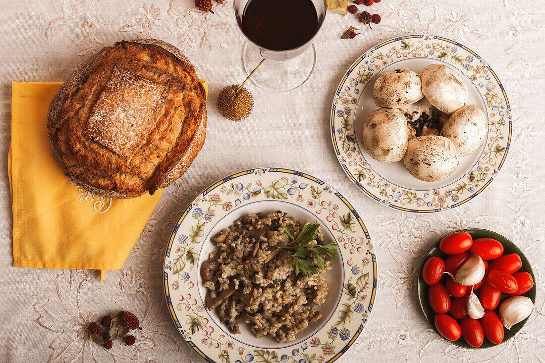 Blick von oben auf eine rustikale Mahlzeit mit hausgemachtem Brot, Pilzrisotto und frischem Gemüse