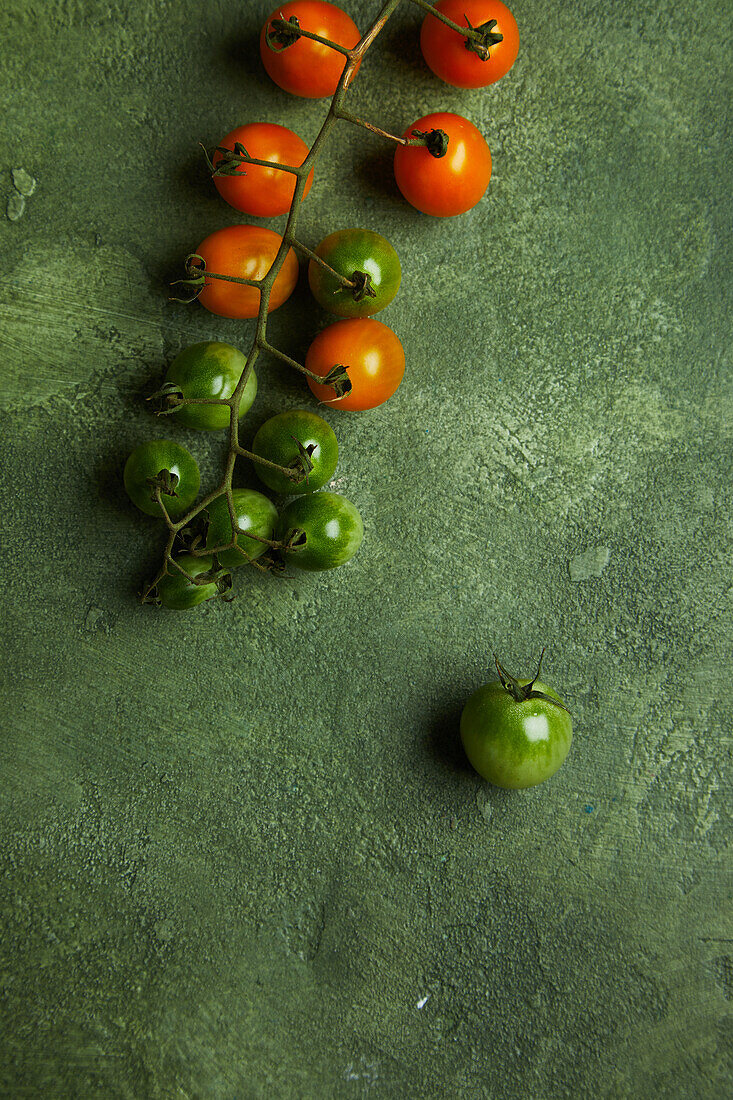 Top view of bunch of fresh ripe and unripen cherry tomatoes placed on green background