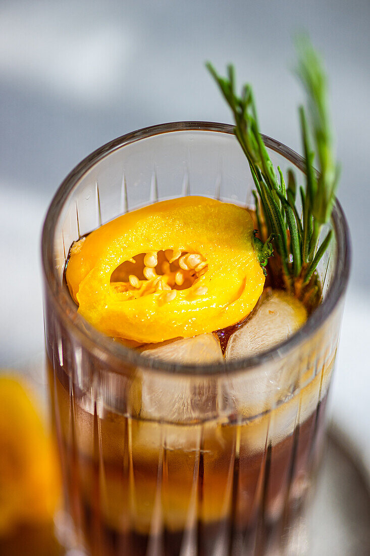 Hoher Blickwinkel auf einen würzigen Margarita-Cocktail mit Eiswürfeln und frischen Fruchtscheiben auf einem Tablett vor grauem Hintergrund