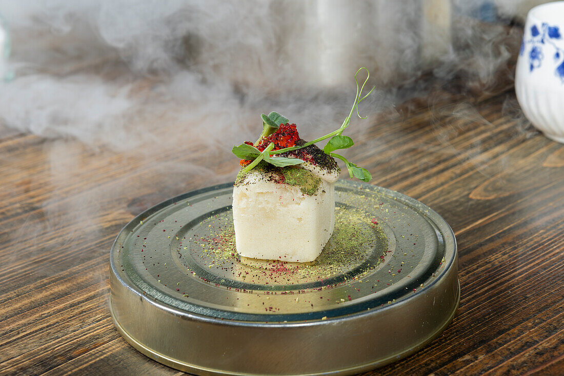 Gourmet fusion dish served with theatrical smoke at a Michelin star restaurant in Zermatt, Switzerland, showcasing local and seasonal ingredients.