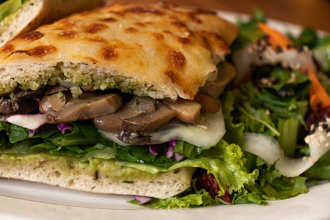 Closeup of tasty baked chapatas with chopped mushrooms fresh lettuce placed on white table against blurred background in light