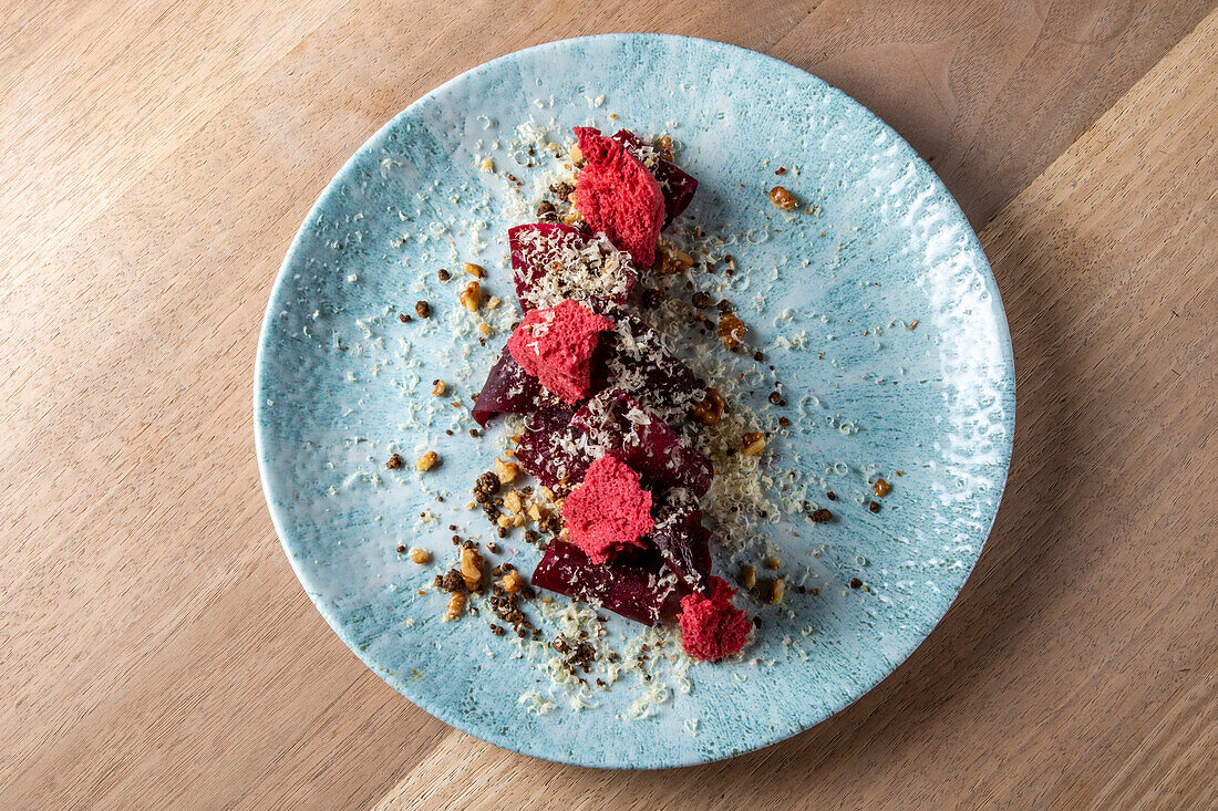 Draufsicht auf ein köstliches Haute Cuisine-Dessert auf einem blauen Teller auf einem Holztisch