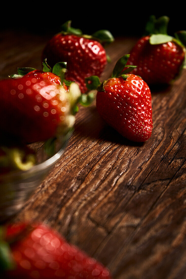 Komposition aus frischen, appetitlichen Erdbeeren mit grünen Blättern, die auf einem Haufen auf einer Holzfläche angeordnet sind