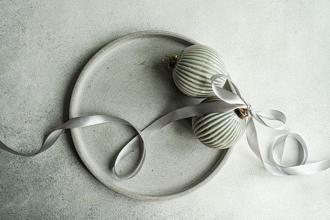 Top view of balls decorated with satin ribbon as symbol of Christmas time placed on gray surface