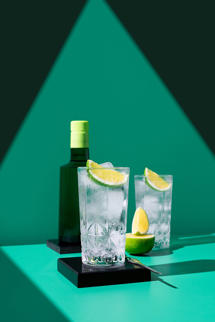 An elegant gin tonic set on a geometric backdrop with vibrant lime slices, casting soft shadows.