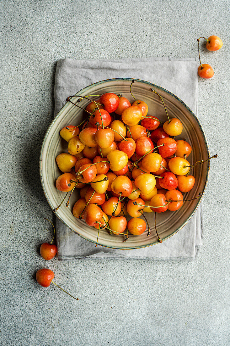 Bowl with organic ripe white sweet cherries on the concrete kitchen table