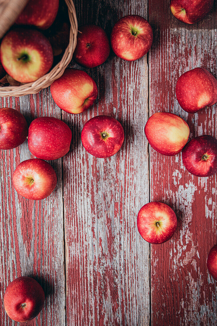 Von oben Weidenkorb gefüllt mit frischen reifen roten Äpfeln auf schäbigen Holzschrank während der Erntezeit platziert