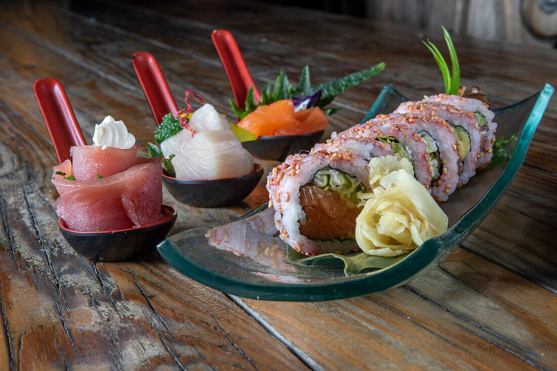 Von oben köstliche Uramaki Sushi und Nigiri Sushi zusammen mit Sashimi in kleinen Schalen auf hölzernem Hintergrund