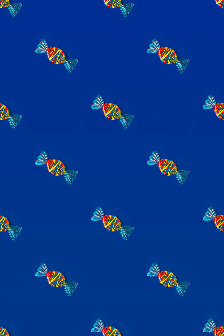 Top view of pattern of whole sweet crystal candies arranged on blue background