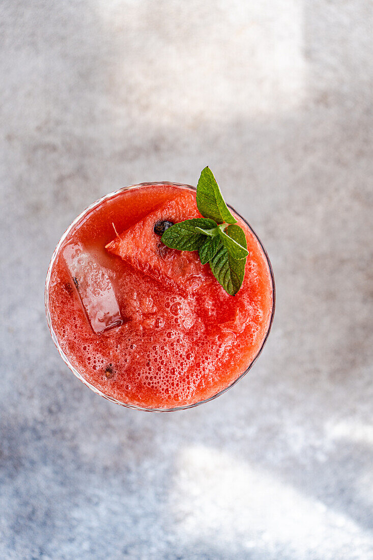 Draufsicht auf ein Glas mit frischem Margarita-Cocktail mit Wassermelonen-Smoothie, bedeckt mit Minzblättern