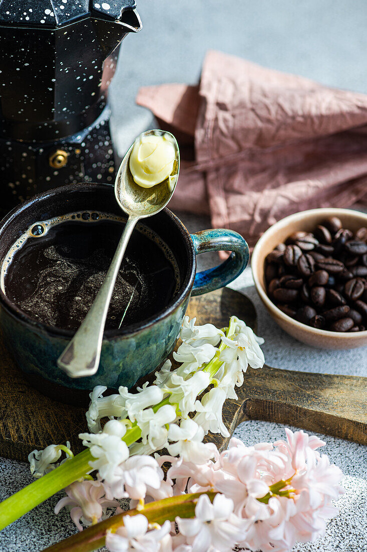 Tasse kugelsicherer ketogener Kaffee in einem Keramikbecher auf einem Betontisch an einem sonnigen Morgen