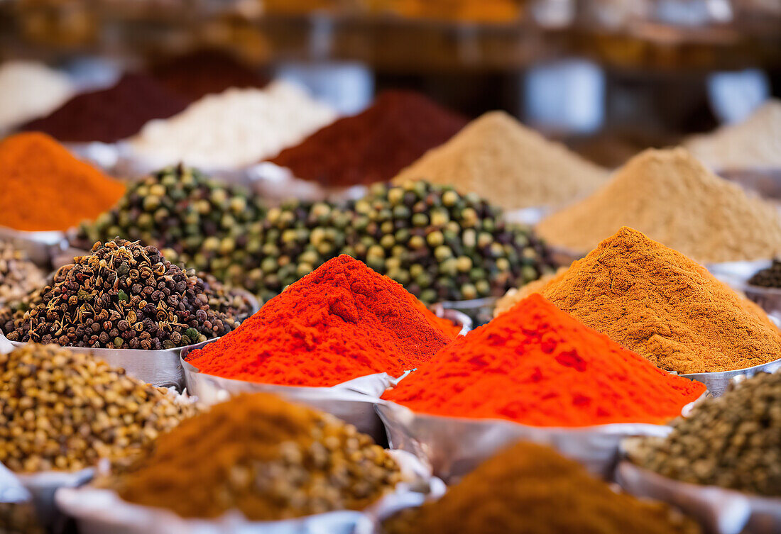 Colorful assorted traditional Moroccan spices placed on stall in market over blur street with people