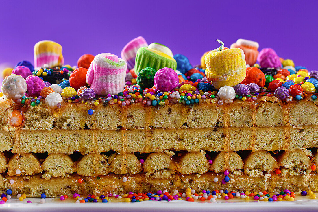 Cross sectional view of Peruvian nougat with glaze and colorful sprinkles placed over purple background