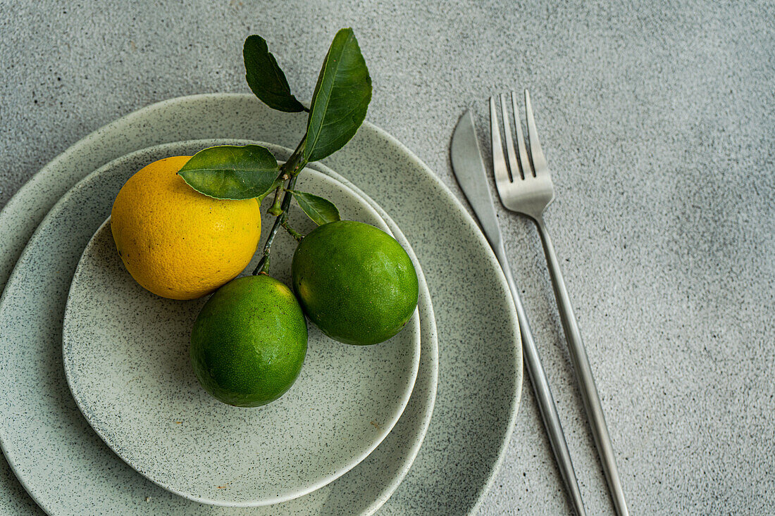 Draufsicht auf gestapelte Keramikteller mit einer Zitrone und zwei Limetten, die moderne Küchenästhetik mit natürlichen Elementen verbinden