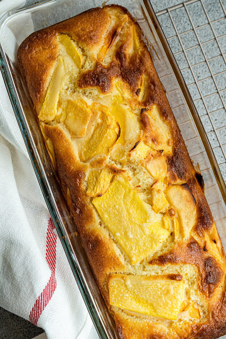 Draufsicht auf einen Pfirsichkuchen der Saison, der auf einem Ofengestell serviert wird, neben einer Serviette auf dem Tisch