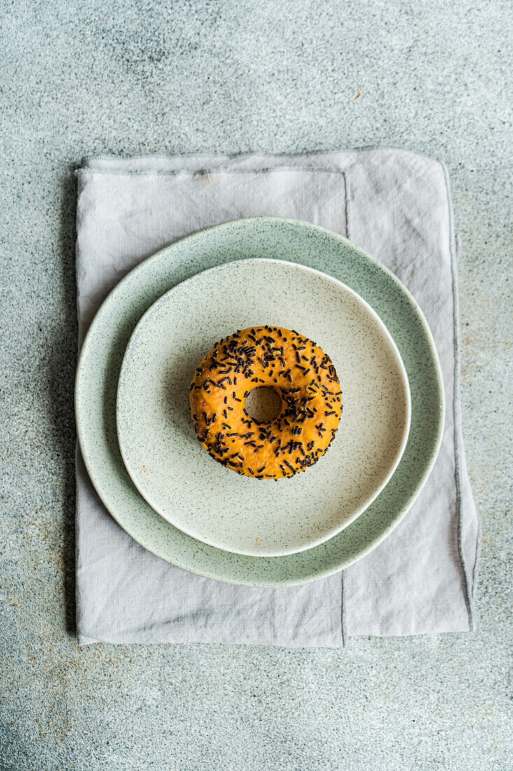 Top view of sweet banana donut placed on gray plate on gray table