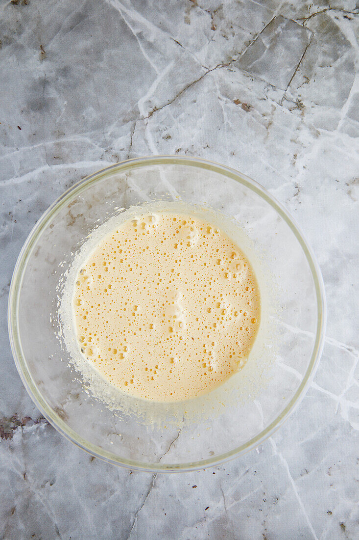 Draufsicht auf Eischnee in einer Schüssel auf einem Marmortisch beim Backen von Gebäck