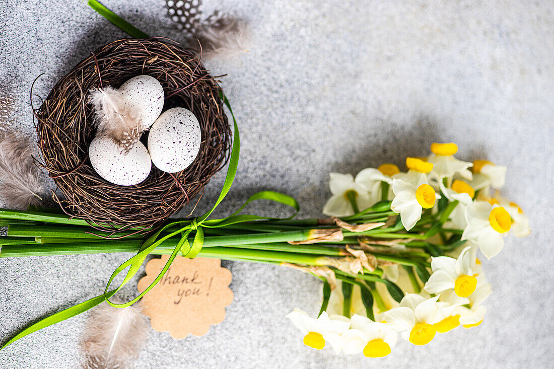 Osterkartenkonzept von oben mit Nest mit Eiern und Narzissenblüten im Strauß