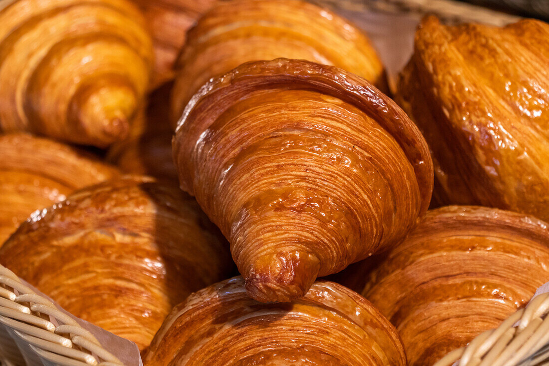 Nahaufnahme von leckeren, frisch gebackenen, knusprigen Croissants in einem Holzkorb in einer Bäckereiküche