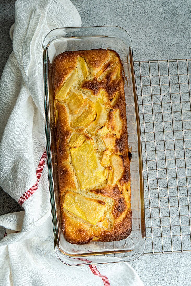 Draufsicht auf einen Pfirsichkuchen der Saison, der auf einem Ofengestell serviert wird, neben einer Serviette auf dem Tisch