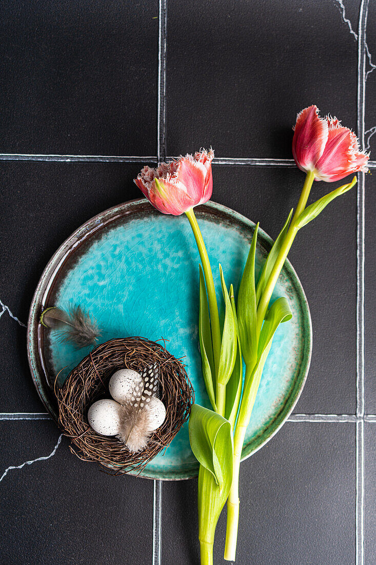 Draufsicht auf einen gedeckten Tisch mit frischen Tulpenblüten auf schwarzem Betonhintergrund