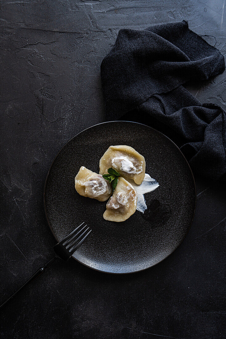 Top view of a tasty traditional Ukrainian dumplings with cherry and sour cream with mint