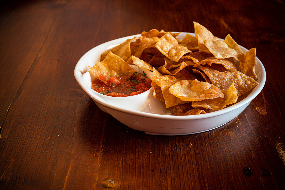 Mexican corn chips with salsa sauce on wooden table