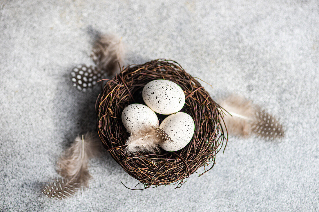 Von oben Nest mit Heu und Eiern auf Betonhintergrund als Osterkartenkonzept