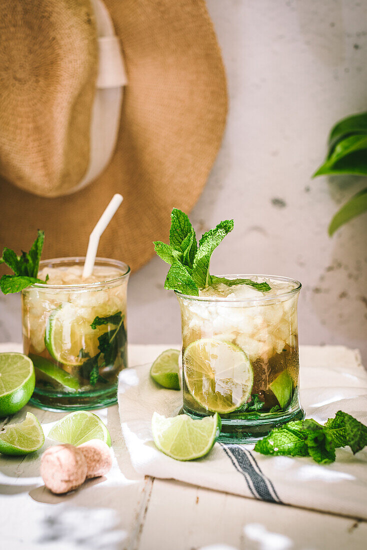 Glasses with cold alcohol Mojito cocktail with cava and fresh limes served with ice and mint leaves on tabl