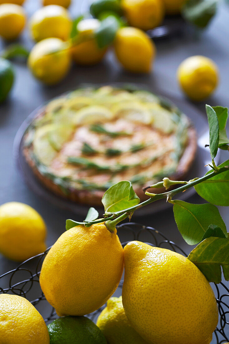 From above to bottom of a blurred lemon tart placed on a table with several lemons