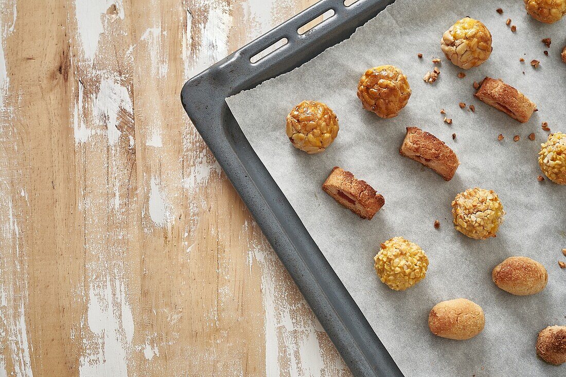 Top view of sweet panellets served on tray placed on wooden table