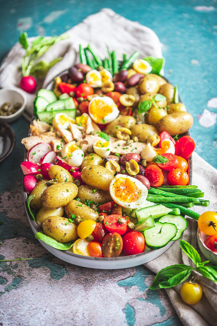 Draufsicht auf einen köstlichen Nicoise-Salat mit frischem Gemüse in einem Tablett auf dem Tisch
