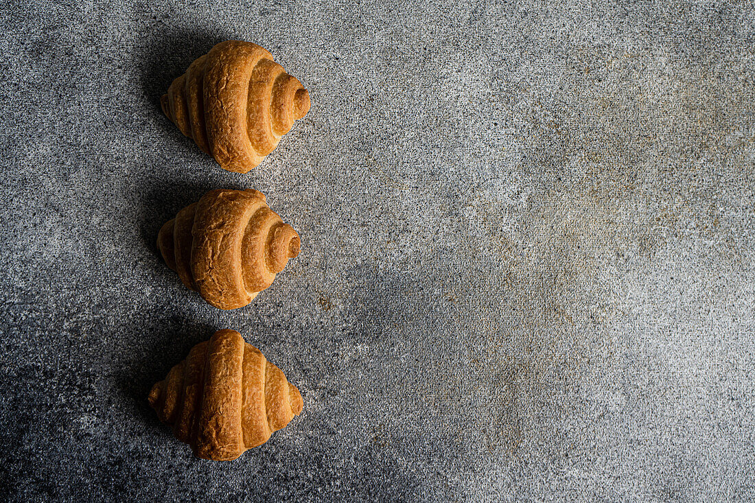 Draufsicht auf frisch gebackene Croissants auf einem Betonhintergrund