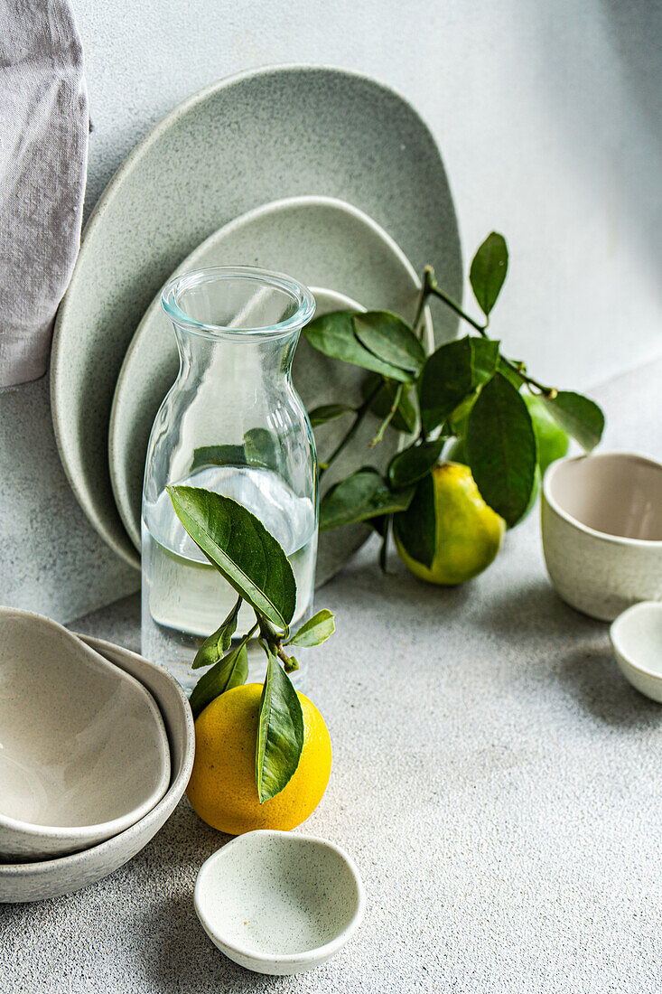 A sophisticated table setting featuring fine ceramic dishes, fresh lemons, and pears on a textured linen backdrop.