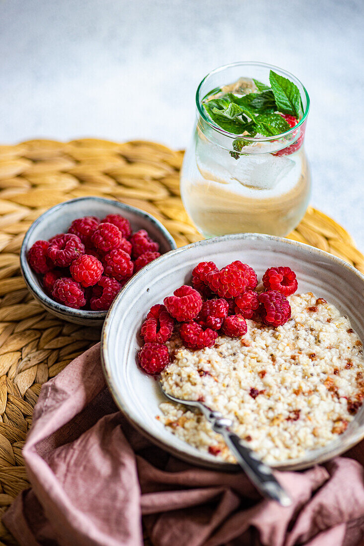 From above healthy breakfast with oatmeal with fresh organic raspberries and homemade lemonade on concrete table