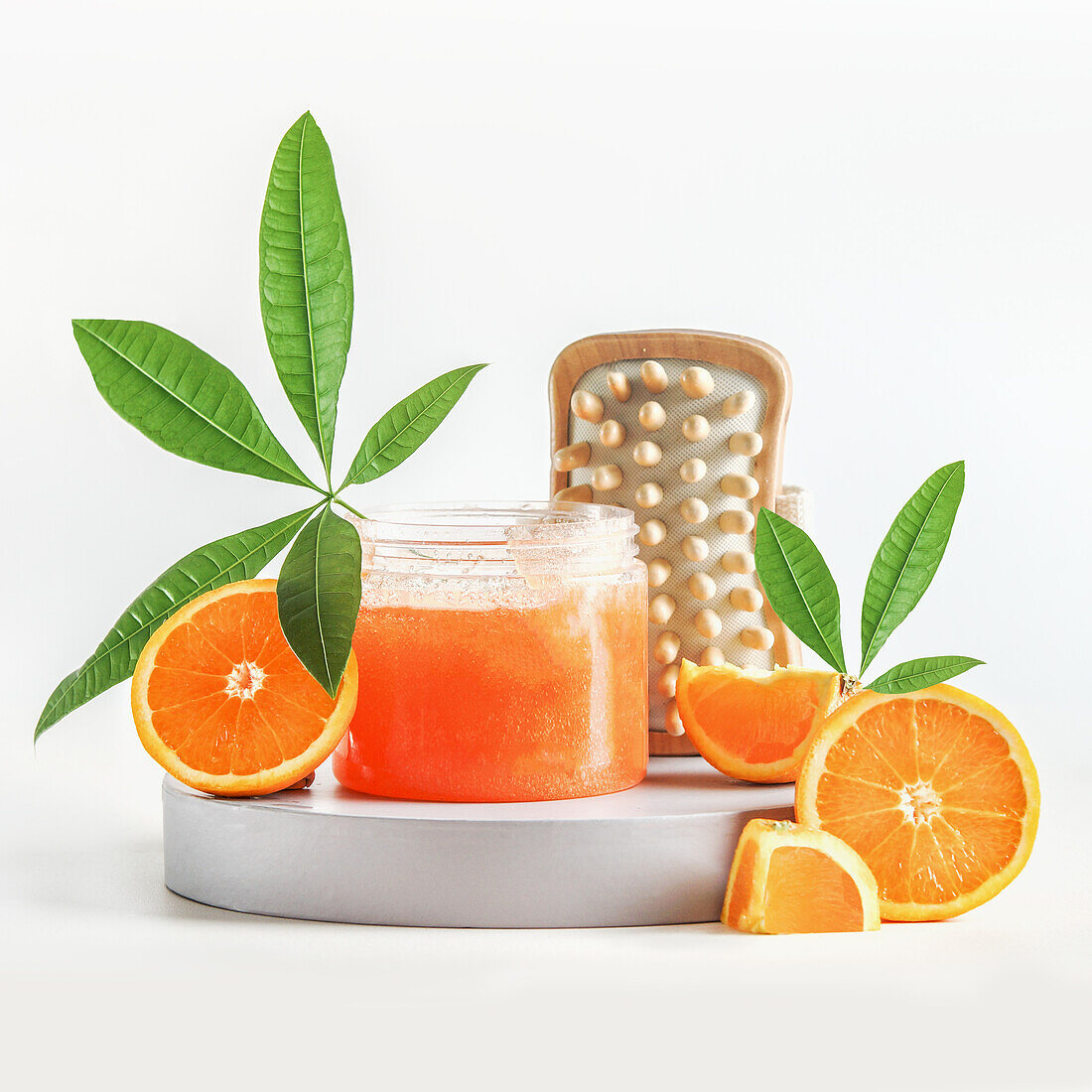 Spa-Setting mit Orangenzucker-Peeling im Glas mit tropischen grünen Blättern, Holzmassagebürste und Orangenfrüchten. Gesunde Hautpflege und Behandlung mit natürlichen Bade- und Wellnessprodukten. Frontansicht