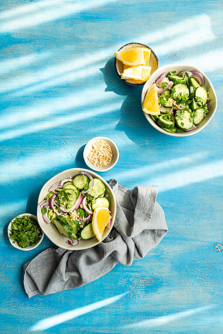 From above of healthy vegetables salads with organic cucumber, red onion, coriander and chopped nuts placed in a blue concrete table